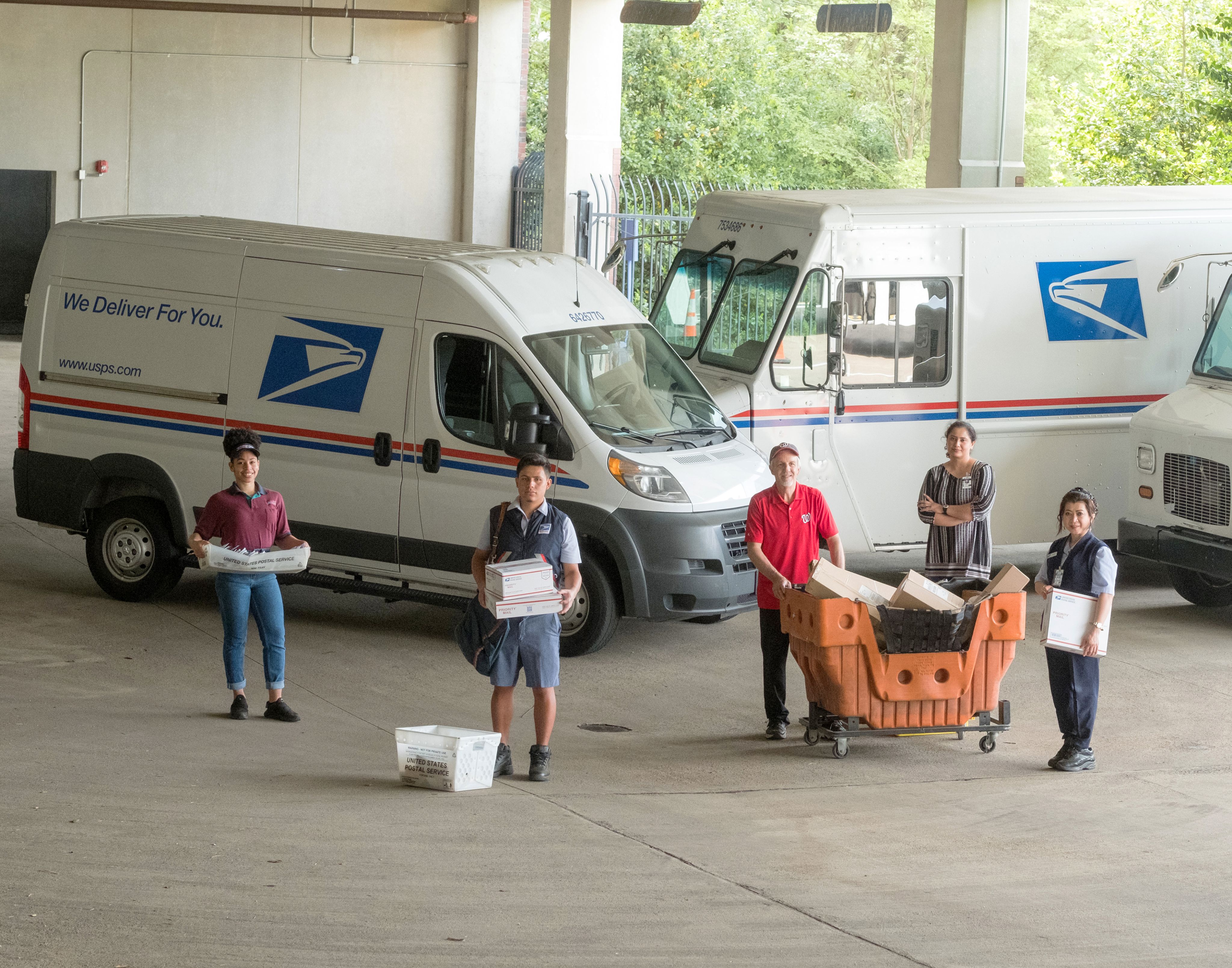 USPS employees in front of electric vehicles