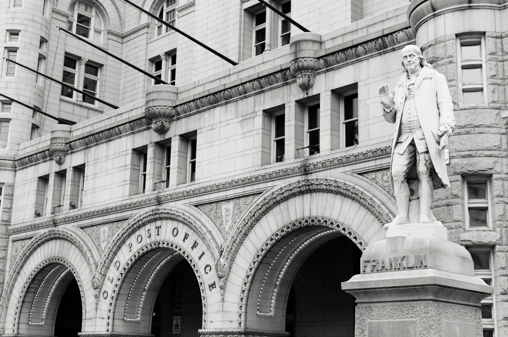 US flags and a statue of Benjamin Frankin outside a post office