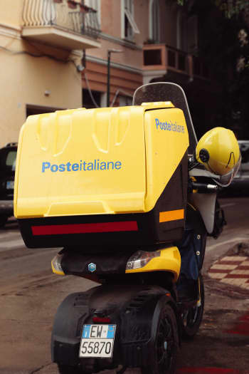 Back view of a Poste Italiane scooter parked on a street in Alghero, Sardinia, Italy.